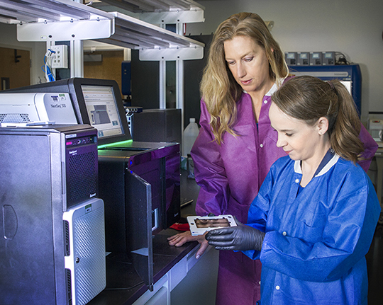 (Left): Principal investigator Jean Challacombe, assisted by Cheryl Gleasner who runs the sequencing machines, sequence Francisella genomes. The device shown is an Illumina NextSeq 500, used in high-throughput sequencing.